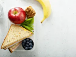 Lunchbox with sandwich, apple, banana, blueberries, snap peas, and granola bite