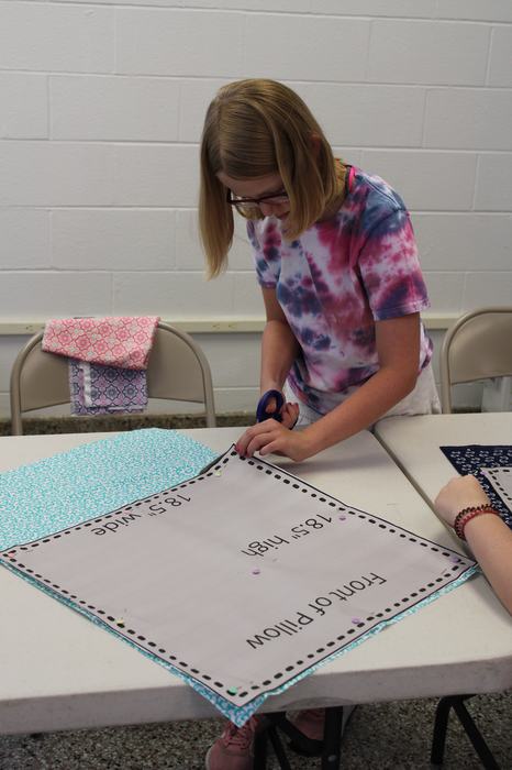 Young girl cutting out fabric for a sewing project.