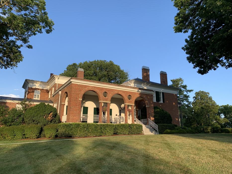 An old brick inn in the middle of a green lawn.