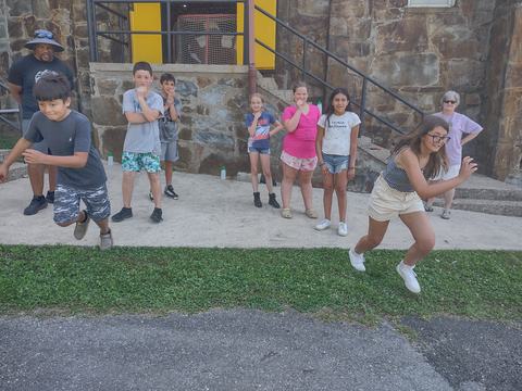 Group of children lined up outdoors, two kids running forward while others watch
