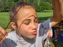 Girl holding fishing pole with hooked sunfish near her face