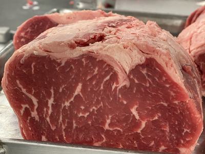 Raw beef roast with marbling resting on a metal display rack