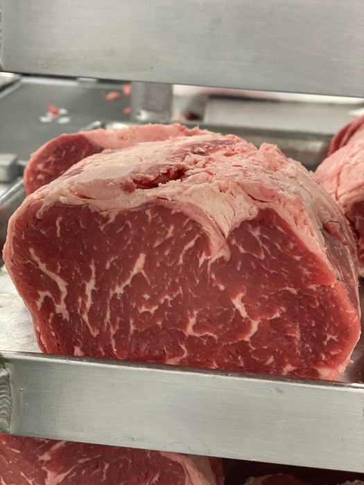A fresh cut of beef on a stainless steel shelf.
