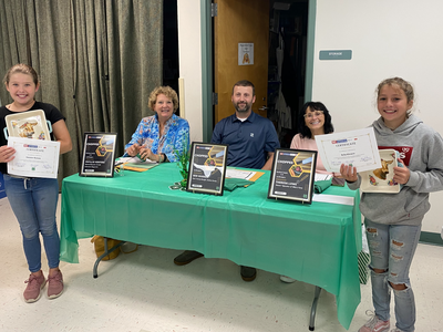 Two girls holding certificates and decorative plates in front of judges' table with CHOPPED signs