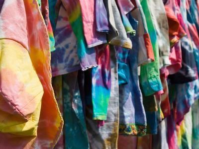 Row of colorful tie-dyed shirts hanging on a rack outdoors