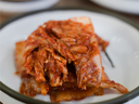 Fermented spicy kimchi (napa cabbage) piled on a white-rimmed plate