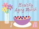 Cereal bowl with berries, plate, utensils and vase of flowers; text "Healthy Aging Month"