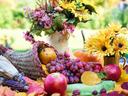 Cornucopia spilling grapes, apples, pumpkin and sunflowers on autumn table