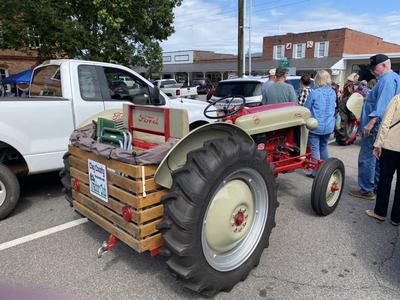 Vintage Ford tractor hitched to wooden crate trailer at downtown street gathering