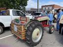 Vintage Ford tractor hitched to wooden crate trailer at downtown street gathering
