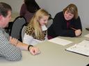 Robbie Denning and Kristy Brown work with 4-H member Keagan on club paperwork.