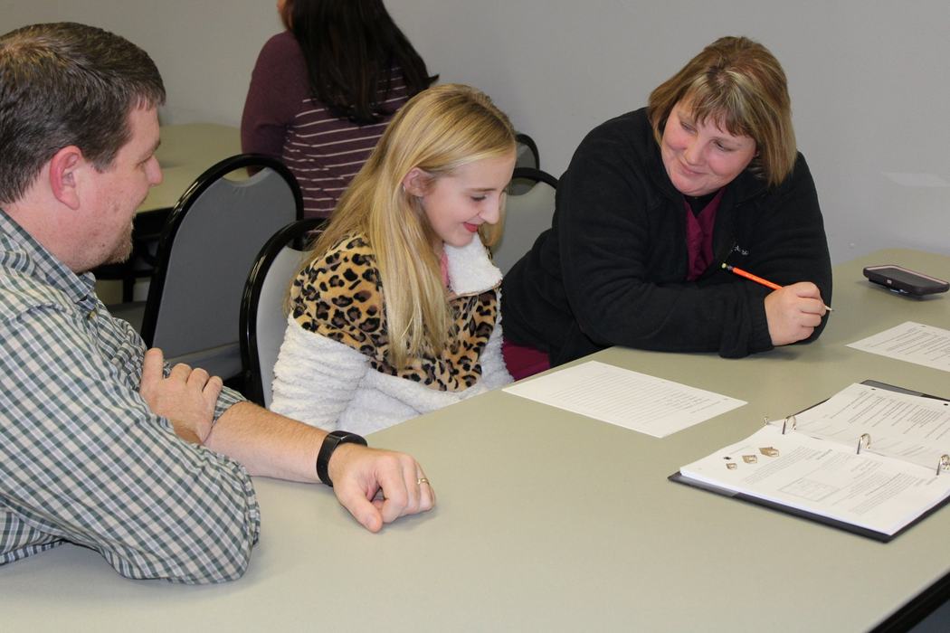 Robbie Denning and Kristy Brown work with 4-H member Keagan on club paperwork.