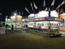 Night carnival food stands lit, signs reading "Funnel Cakes", "Elephant Ears", "Fried Dough"