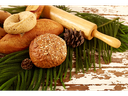 Assorted breads, rolling pin, and pine cones on evergreen sprigs over chipped wooden table