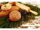 Assorted breads, rolling pin, and pine cones on evergreen sprigs over chipped wooden table