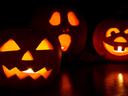 Three lit jack-o'-lanterns with carved faces on a dark surface