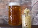 Jar of sauerkraut with fork lifting shredded cabbage, beer stein blurred in background