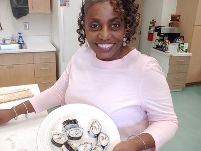 Woman holding a plate of sushi rolls in a kitchen