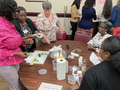 Group around table preparing chopped vegetables; paper reads "ADD: 1 minced jalapeno"