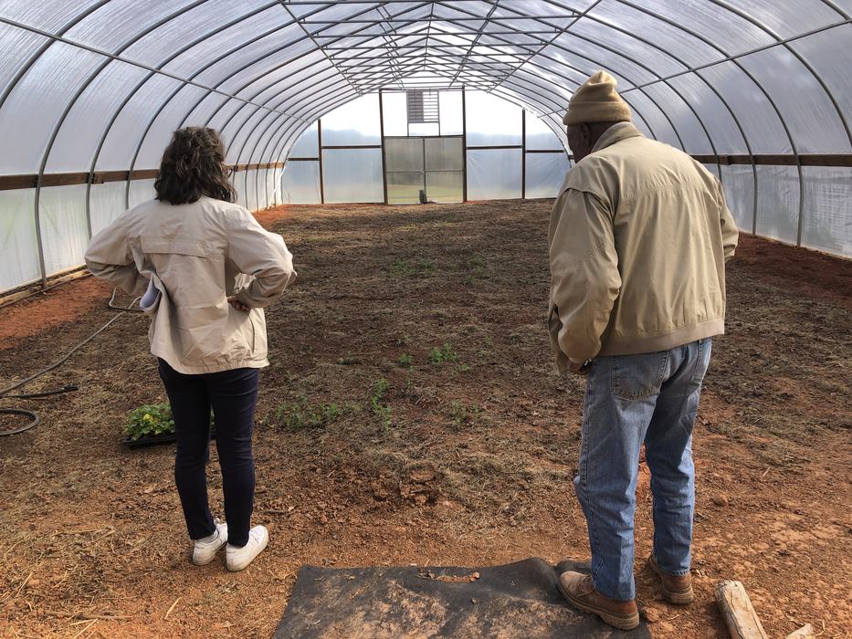 Two people inspect an empty greenhouse.