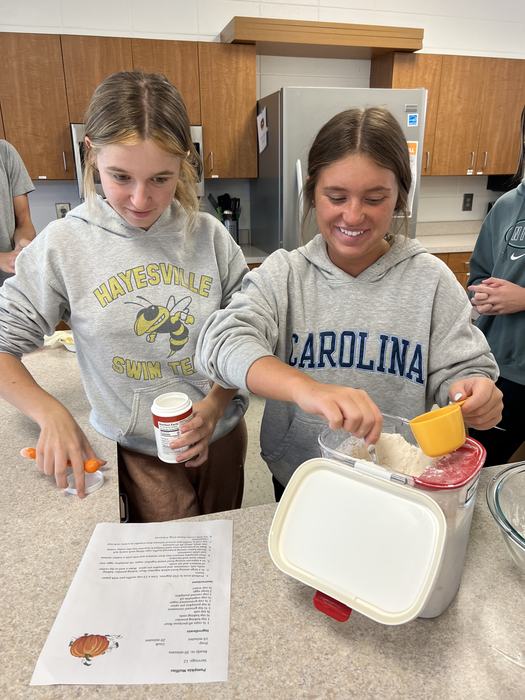 Students measure dry ingredients for use in baking.