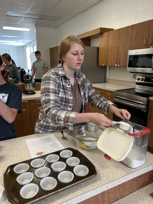 A student measures out dry ingredients from an air tight container.