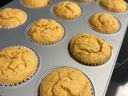 Golden-brown muffins in paper liners in a metal muffin tin on a stovetop