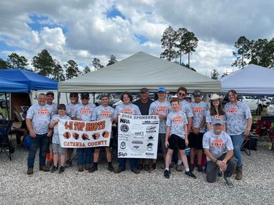 A group of 4-H Top Shots posing together with their banner.