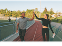 Two runners on a track giving each other a high-five, each holding a water bottle