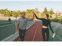 Two runners on a track giving each other a high-five, each holding a water bottle