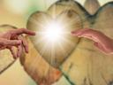 Left and right hands reaching toward bright central light, blurred hearts behind