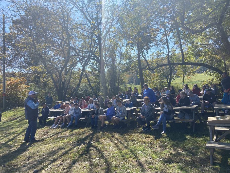 A group of students listening to a man speak outside.