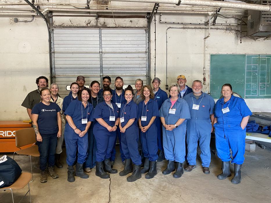 A group of people in blue coveralls standing in front of a garage door.