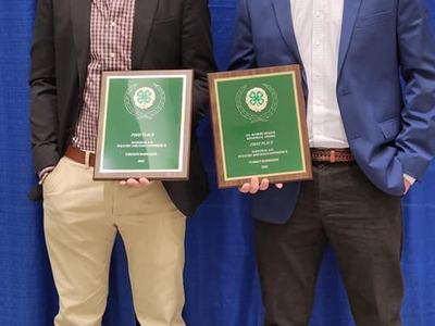 Two young men in formal clothing holding 4-H plaques.