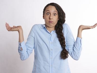 Young woman in a blue shirt with her palms facing upward looking confused