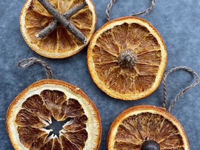 Four dried orange-slice ornaments with twine loops and natural accents