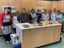 Group of people standing behind a kitchen island with prepared dishes; aprons read "EFNEP."