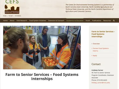 Woman in hi‑vis jacket holding a crate of oranges in a warehouse; text: "Farm to Senior Services"