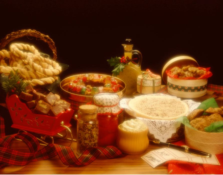Holiday spread of cookies, candies, jars, ribbon and decorative sleigh on wooden table
