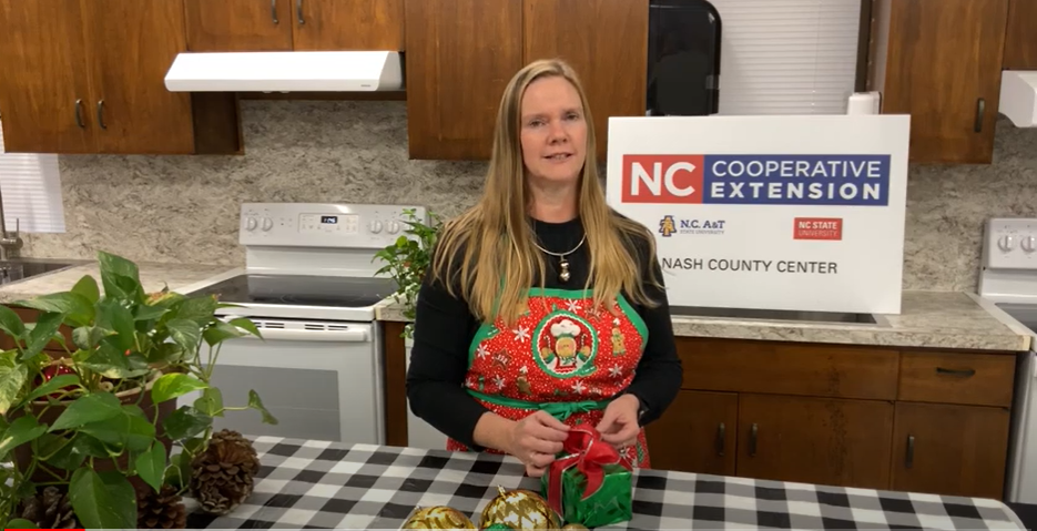 A woman in a kitchen wrapping a present.