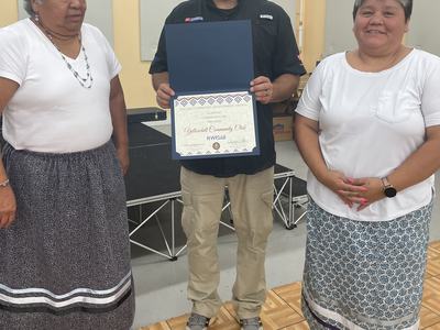  A man presents a certificate to two women.