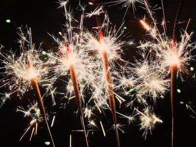 Five handheld sparklers burning and emitting bright sparks against a dark background