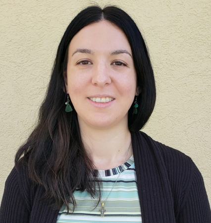 Headshot photo of Paige wearing a striped shirt and black sweater