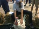 Girl wearing mask seated on hay holding a large white turkey at a livestock show