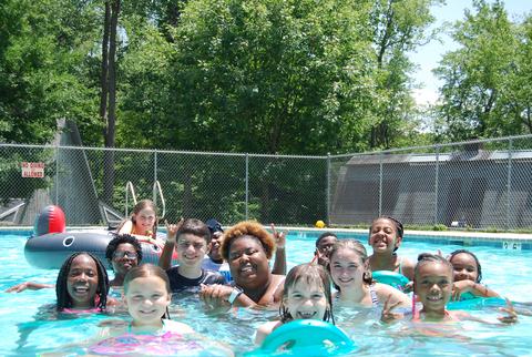 Children and one adult together in a swimming pool; sign reading "NO DIVING ALLOWED"