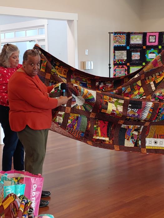 An African American woman displays her quilt.