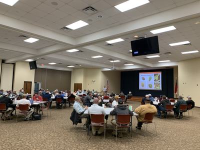 Attendees in conference room watching presenter and slide Stink Bugs in Soybean 101