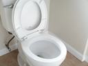 White toilet bowl with open seat positioned in a bathroom corner