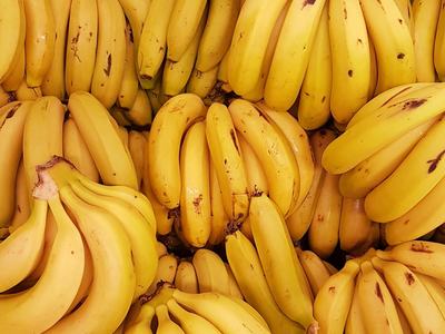 Bunches of ripe yellow bananas stacked closely in a produce display