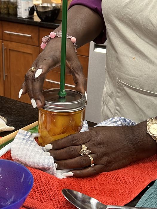 A person sealing the lid of canned produce
